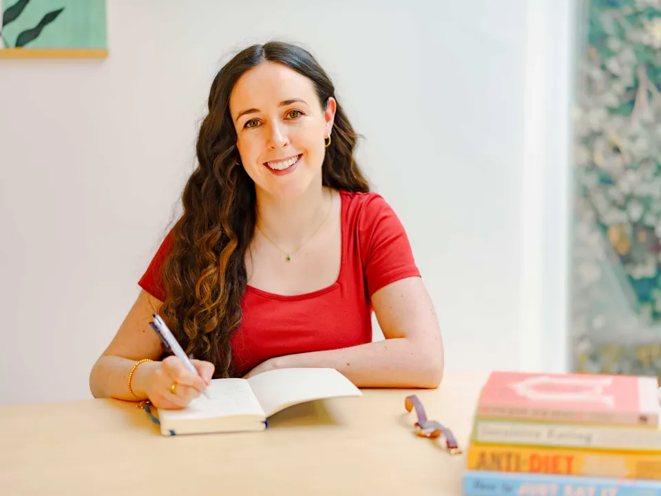 Maeve writing notes at her desk beside books on intuitive eating
