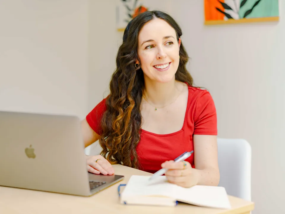 Maeve Hanan at her desk with her laptop and notebook