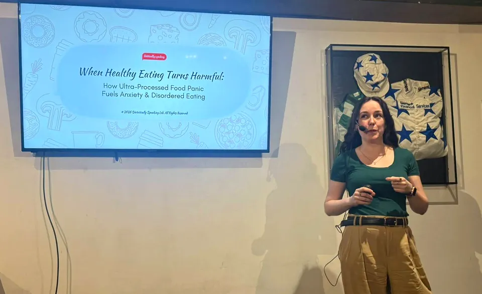 Maeve Hanan giving her talk “When Healthy Eating Turns Harmful” beside a screen showing the title slide